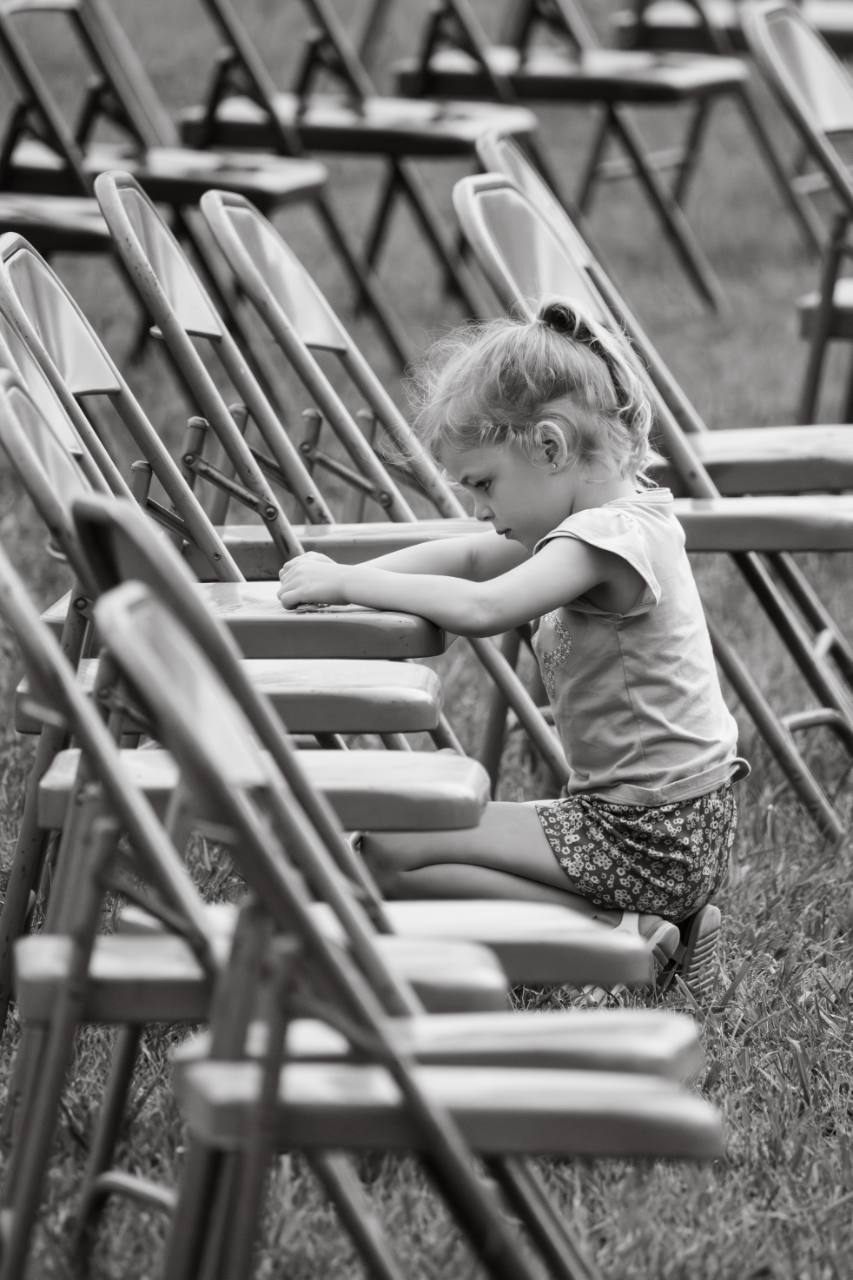 Black and white photo of a young child sitting between event chairs