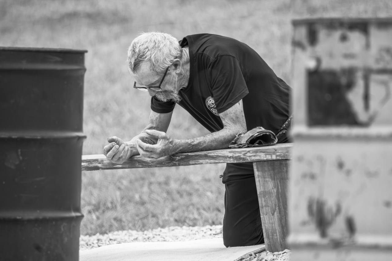 Black and white candid photo of a man leaning over a wooden rail